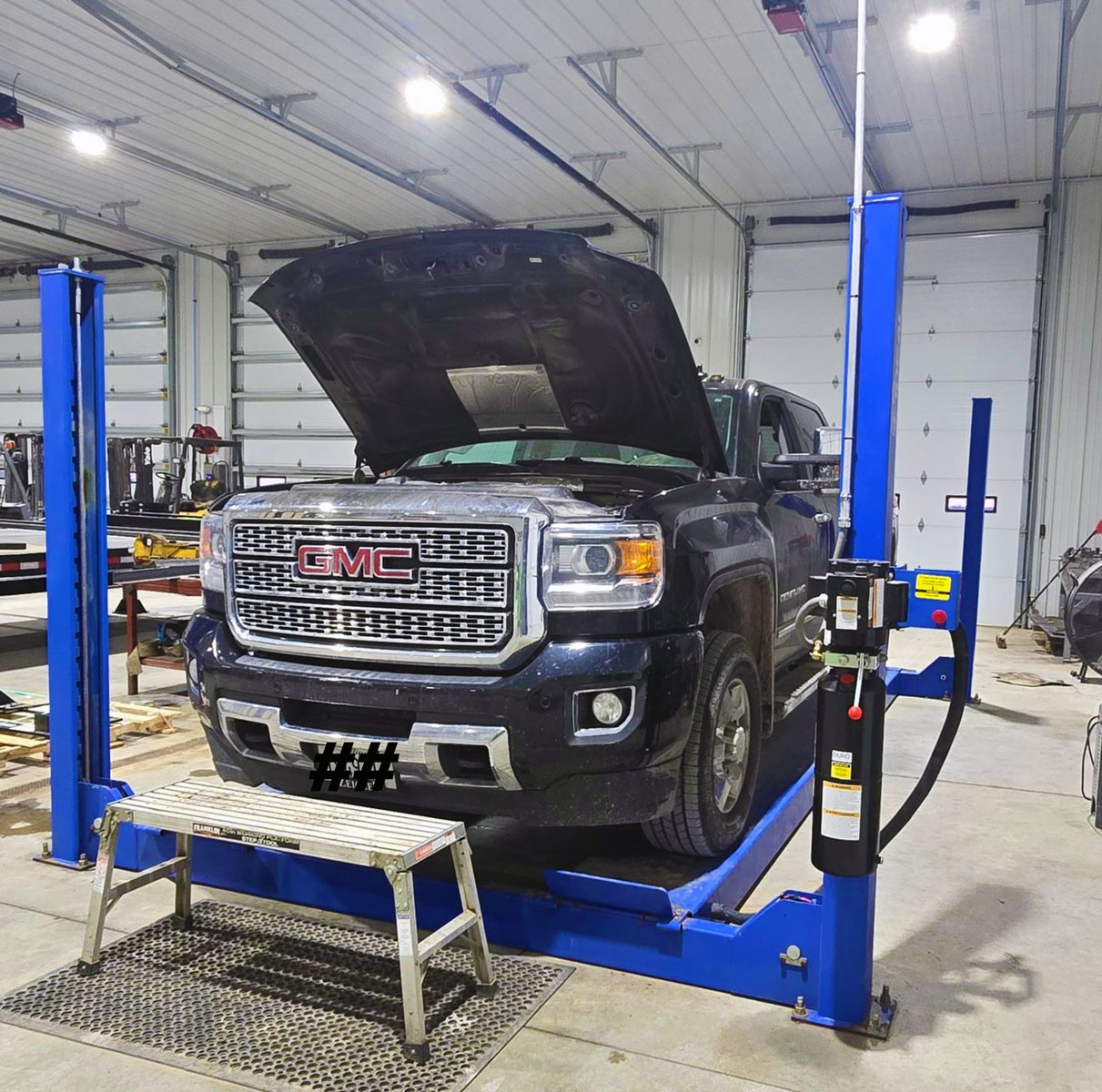 GMC pickup raised on the two-post lift inside the Illini Truck & Trailer shop